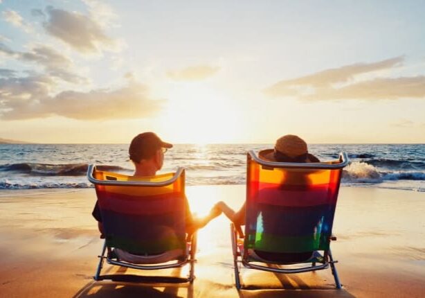 Two people sitting in lawn chairs on the beach